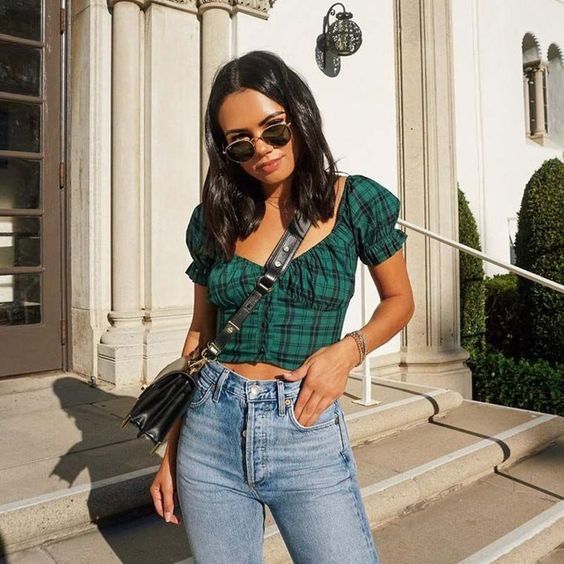 a grunge yet romantic outfit with blue jeans, a plaid emerald crop top with puff sleeves and a black bag