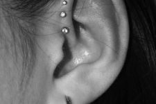 a lobe piercing, a flat piercing and stacked helix piercings accessorized with shiny studs and a hoop earring