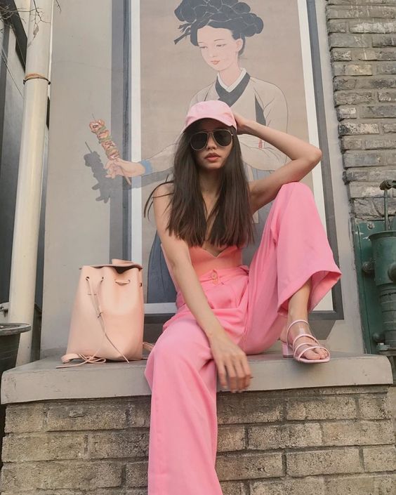a pink strap top, pink paper bag pants, a pink cap, heels and a blush backpack for summer