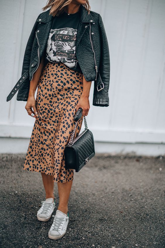 a printed tee, a leopard print midi skirt, white sneakers, a black leather jacket and a black bag