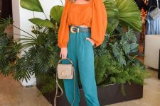 a special occasion look with an orange crop top with long puff sleeves, green pants, silver shoes and a shiny bag