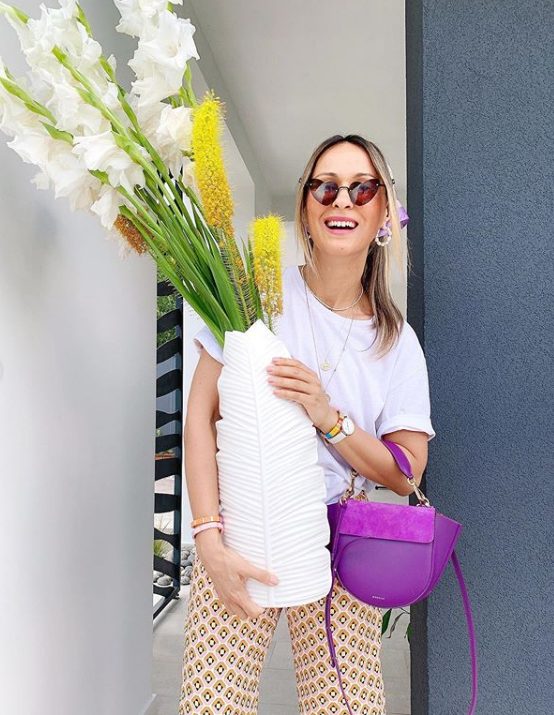 a summer look with a white tee, printed pants, a purple leather and suede bag and heart-shaped sunglasses