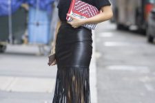 a total black look with a tee, a leather fringe midi skirt, heels and red frame glasses