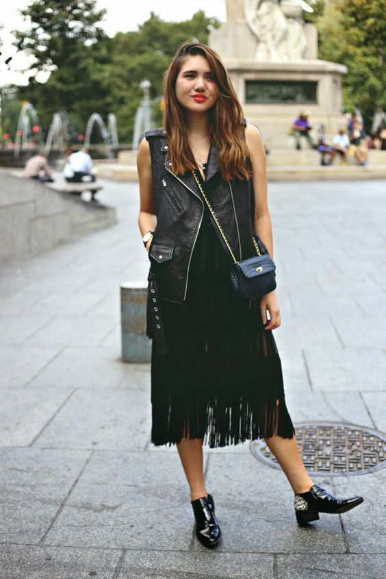 a total black outfit with a top, a fringe midi skirt, a leather waistcoat, shoes and a crossbody