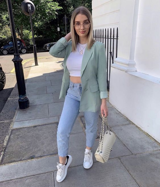 a white crop top, blue high waisted jeans, a mint green blazer, white sneakers and a neutral bag