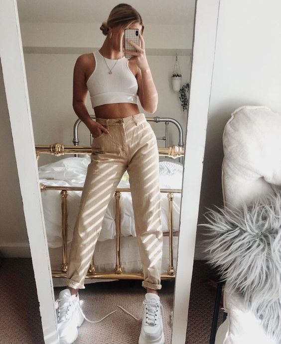 a white halter crop top, tan high waisted jeans, white trainers for a 90s inspired look