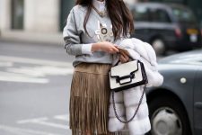 a white shirt, an embellished sweatshirt over it, a tan fringe midi skirt, silver shoes and a two-tone bag
