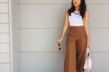 a white sleeveless top, brown culottes with pockets, chain necklaces, two tone shoes and a pink bag