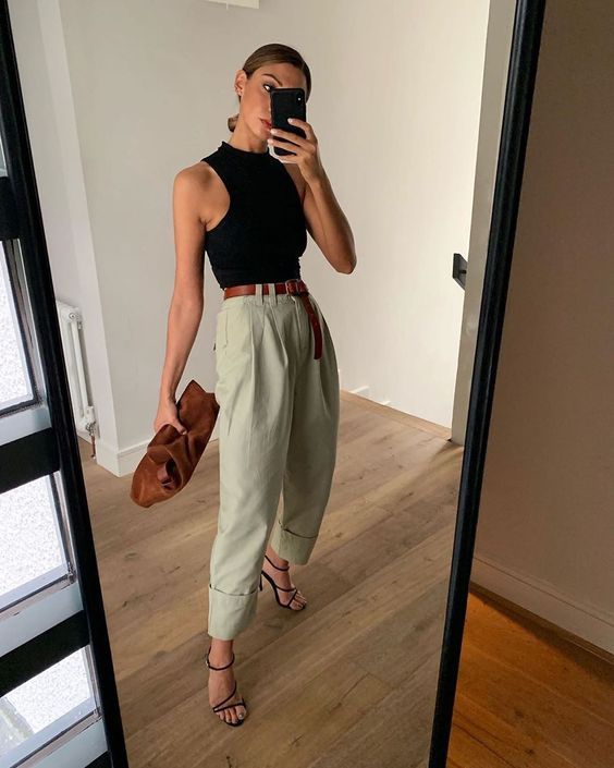 an edgy outfit with a black halter top, olive green baggy pants, black strappy sandals and a brown clutch