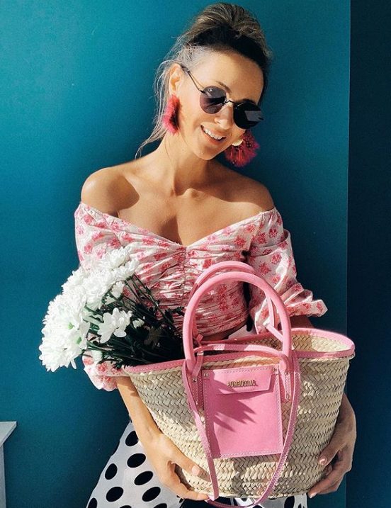 an off the shoulder pink floral crop top, polka dot black and white pants and a pink straw bag