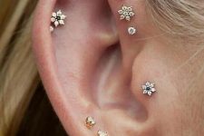 delicate stacked piercings on the lobe, helix and tragus, with mix and match pearl studs and floral ones