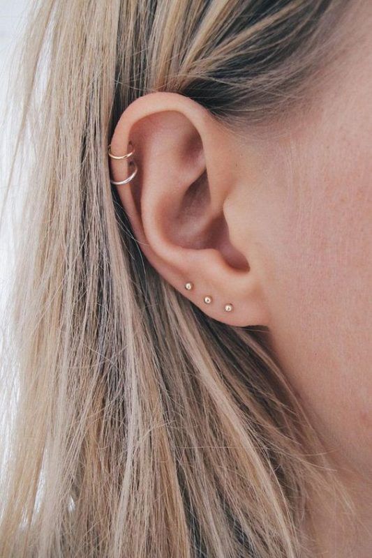 stacked lobe piercings with minimalist gold stud earrings and stacked helix piercings with hoop earrings