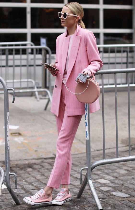 a girlish work outfit with a pink thin striped pantsuit, a light pink tee, light pink sneakers and a dusty pink bag