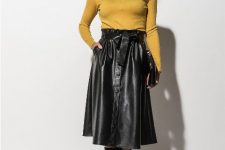 With yellow turtleneck, clutch and black boots