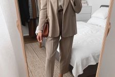 a beige suit with cropped pants, a matching top, white sneakers and a brown bag