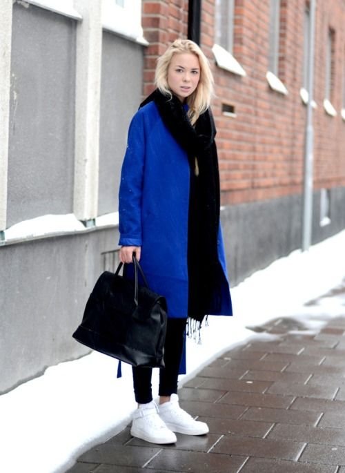 a black hoodie, black skinnies, white trainers, a black bag and an electric blue knee coat for a bold touch