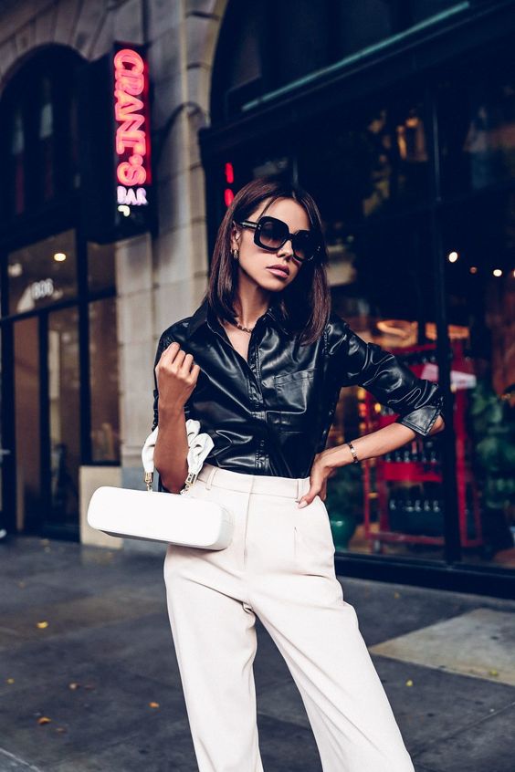 a black leather shirt, creamy pants, a creamy bag of a quirky shape for a unique and trendy look