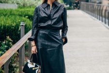 a black leather shirt plus an A-line leather midi, brown boots and a bold printed bag