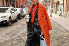 a bold look with an orange top, a windowpane suit, black platform shoes and a statement orange coat