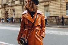 a chic fall outfit with a rust-colored lacquer trench, a black chain crossbody and a black beret