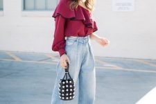a fall party look with a purple one shoulder top, slouchy jeans, black heels and a bucket bag with pearls