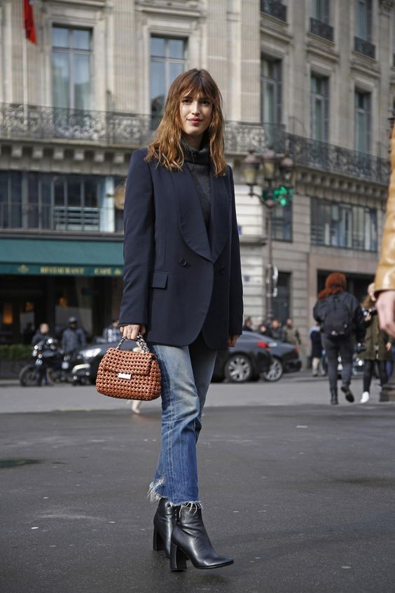 a graphite grey turtleneck, a navy tux, light blue jeans with a raw hem, black booties and a brown woven bag
