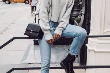 a grey oversized cropped sweater, light blue mom jeans, black boots and a black bag