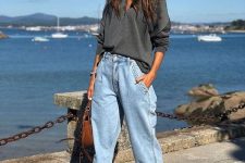 a grey oversized shirt, blue slouchy jeans, two tone trainers and a brown bag