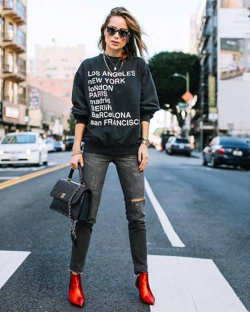 a printed sweatshirt, black ripped jeans, a black bag and burnt orange shiny booties