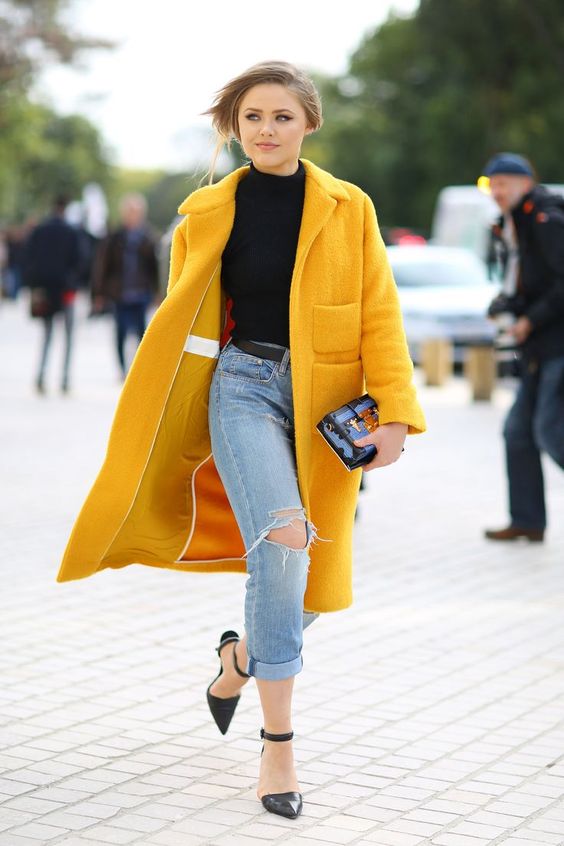 a super chic look with a black turtleneck, blue ripped jeans, black ankle strap shoes and a sunny yellow faux fur coat