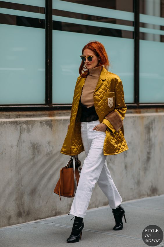 a tan turtleneck, white jeans, black boots, a gold metallic quilted jacket, a tan tote
