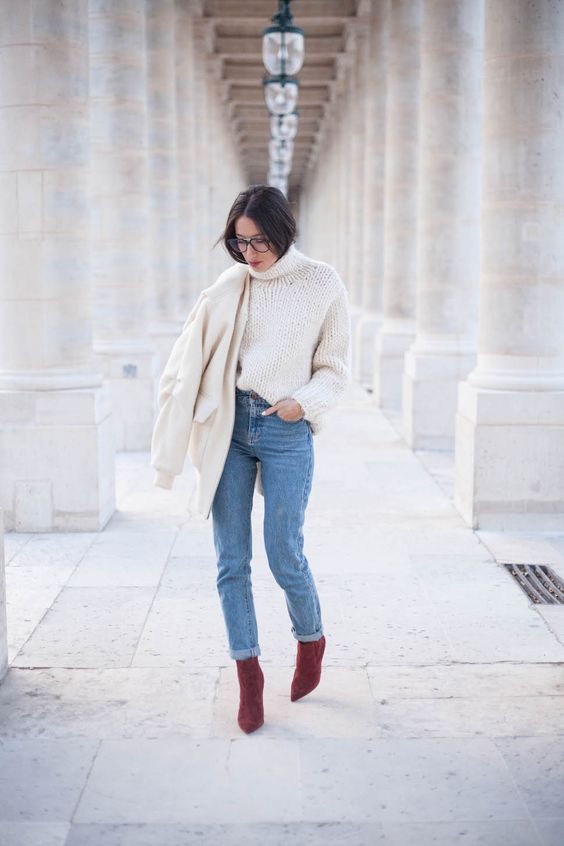 a white chunky knit sweater, blue jeans, purple suede booties and a creamy bomber jacket