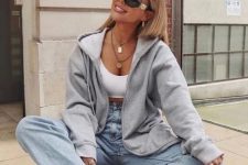 a white crop top, light blue straight jeans, a grey hoodie, white trainers and a printed bag