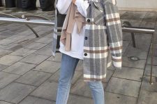 a white hoodie, blue jeans, white sneakers, a grey plaid shirt jacket and a tan scarf
