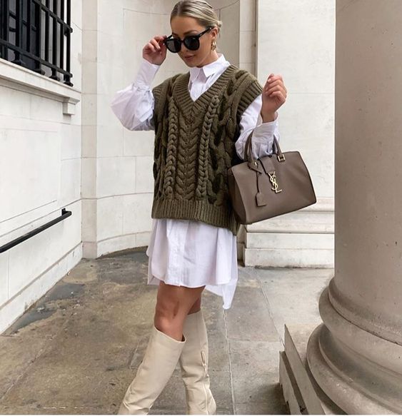 a white oversized shirtdress, an olive green knit vest, creamy boots and a grey bag