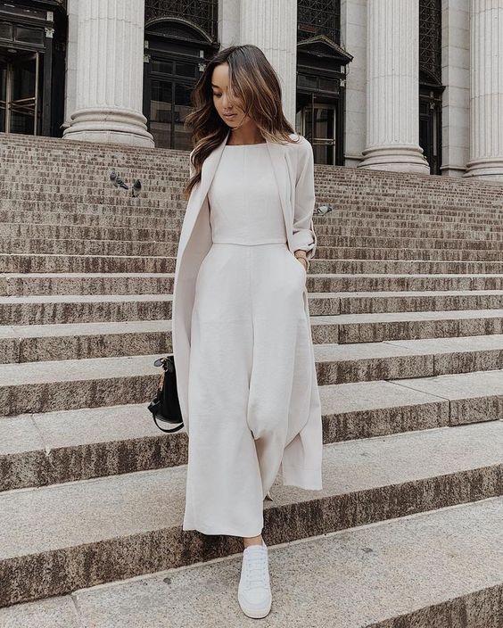 a white plain jumper with culotte pants, a white trench, sneakers and a black bag