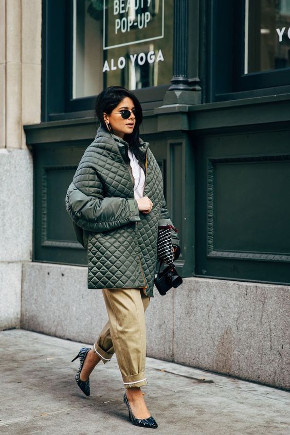 a white shirt, tan slouchy pants, printed shoes, an olive green quilted jacket and a black bag