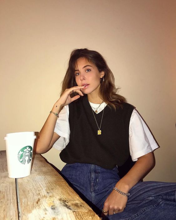 a white tee, a black knit vest, blue jeans and layered necklaces for a relaxed 90s inspired look