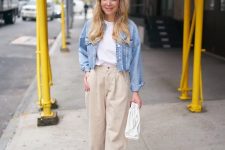a white tee, a blue denim jacket, tan slouchy jeans, blue heeled mules and a white clutch