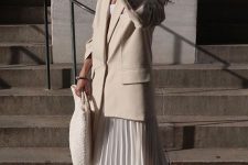 a white top, a white pleated midi skirt, an oversized creamy blazer, brown square toe boots and a white woven bag
