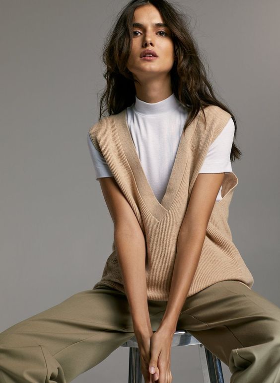a white turtleneck, a tan knit vest, olive green pants for a casual fall outfit