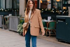 a white turtleneck, a tan oversized blazer, blue straight leg jeans, burgundy square toe booties and a tan bag