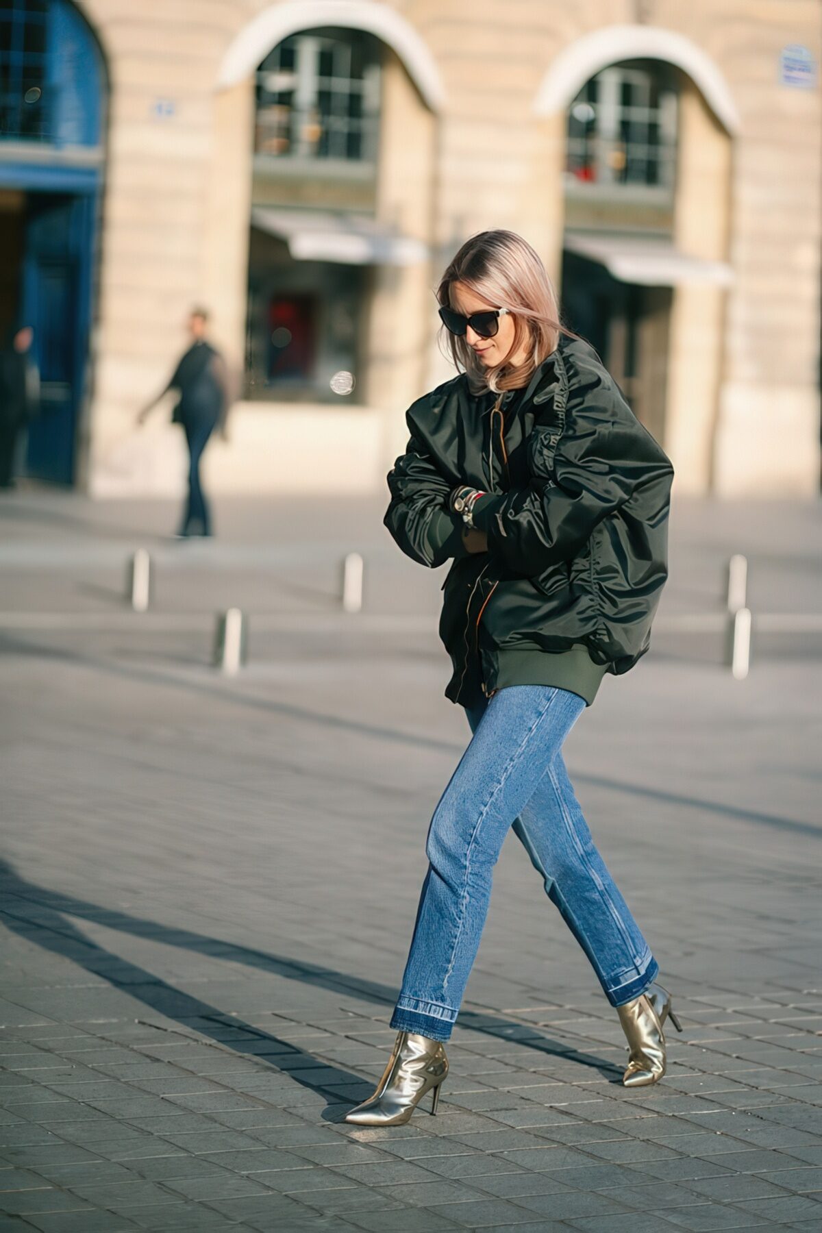 An oversized black bomber jacket, blue jeans, metallic booties for a stylish and bold fall outfit