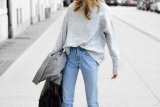 an oversized grey cashmere sweater, blue jeans, white pointed toe boots and a black bag