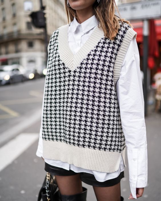 an oversized white shirt, a printed oversized knit vest, black leather shorts, tights for the fall