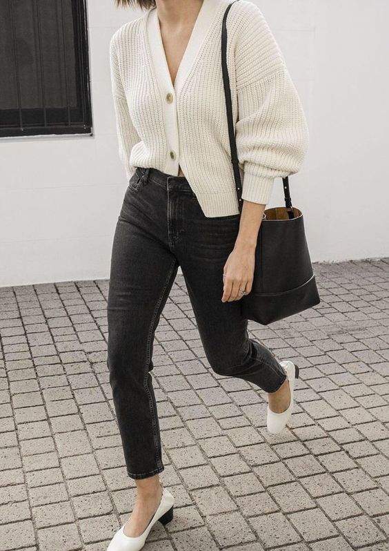 black denim, a white chunky knit cardigan, white shoes and a black bucket bag