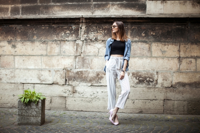 With denim jacket, black crop top, sunglasses and pale pink shoes