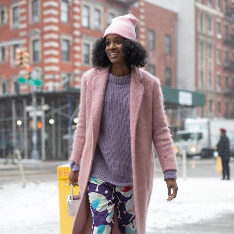 With lilac sweater, colorful pants, mini bag and pink coat