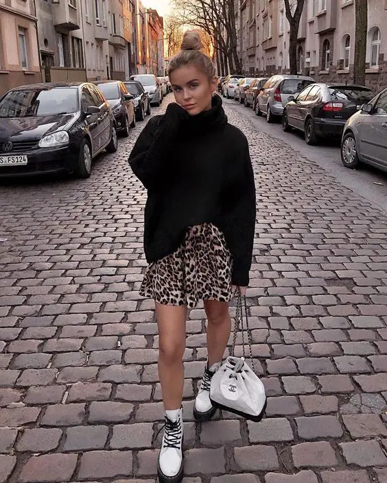 a black oversized turtleneck sweater, a leopard mini skirt, white combat boots and a white bag