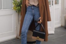 a camel turtleneck, blue cropped skinnies, black moccasins, a two tone bag and a brown coat